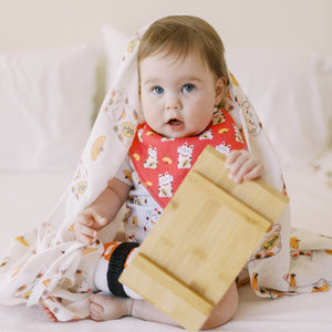 cute baby playing with a tray in lucky cat swaddle and bib