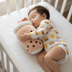 Baby sleeping in a crib with a plush boba toy