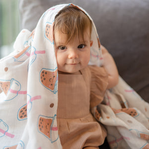 cute baby playing with the wee bean organic cotton and bamboo swaddle in boba bubble tea