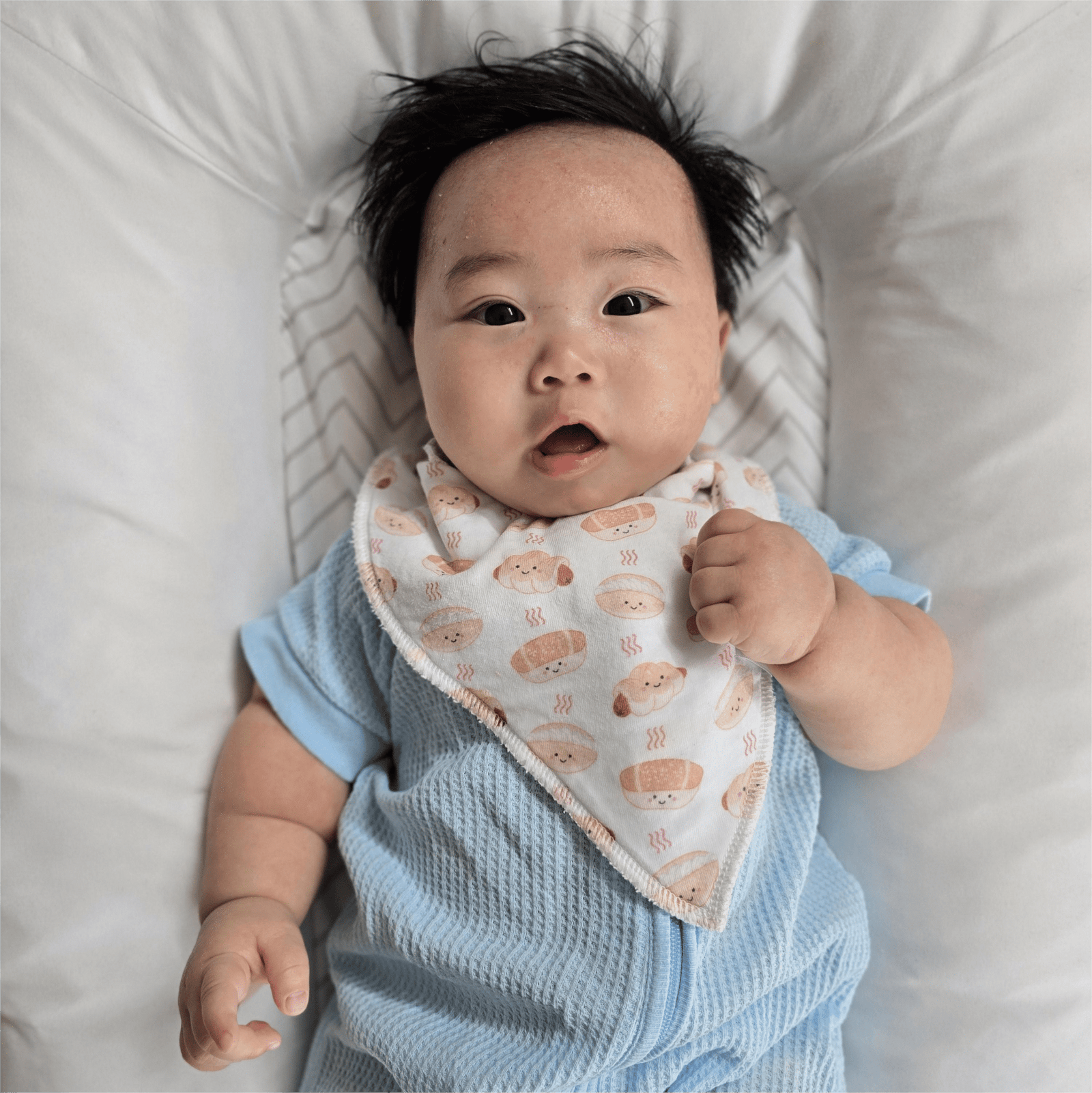 Cute baby boy wearing sky blue onesie and The Wee Bean's Bakery Bun Bib
