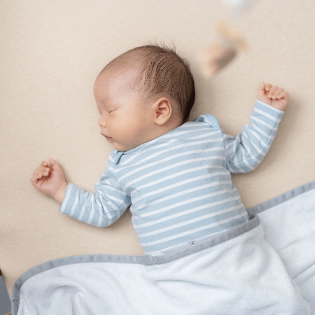 A sleeping baby with stripe onesie and blanket