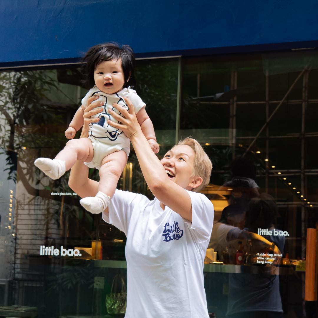 Mom is holding her baby wearing The Wee Bean and Little Bao's collaboration onesie