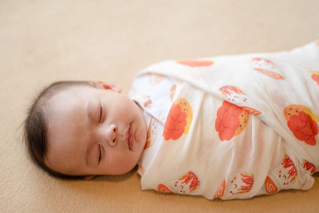 Sleeping baby wrapped in The Wee Bean's best-selling swaddle