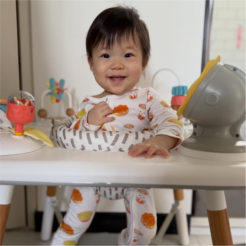 A baby sitting on the bouncer with The Wee Bean's Bamboo Convertible Romper