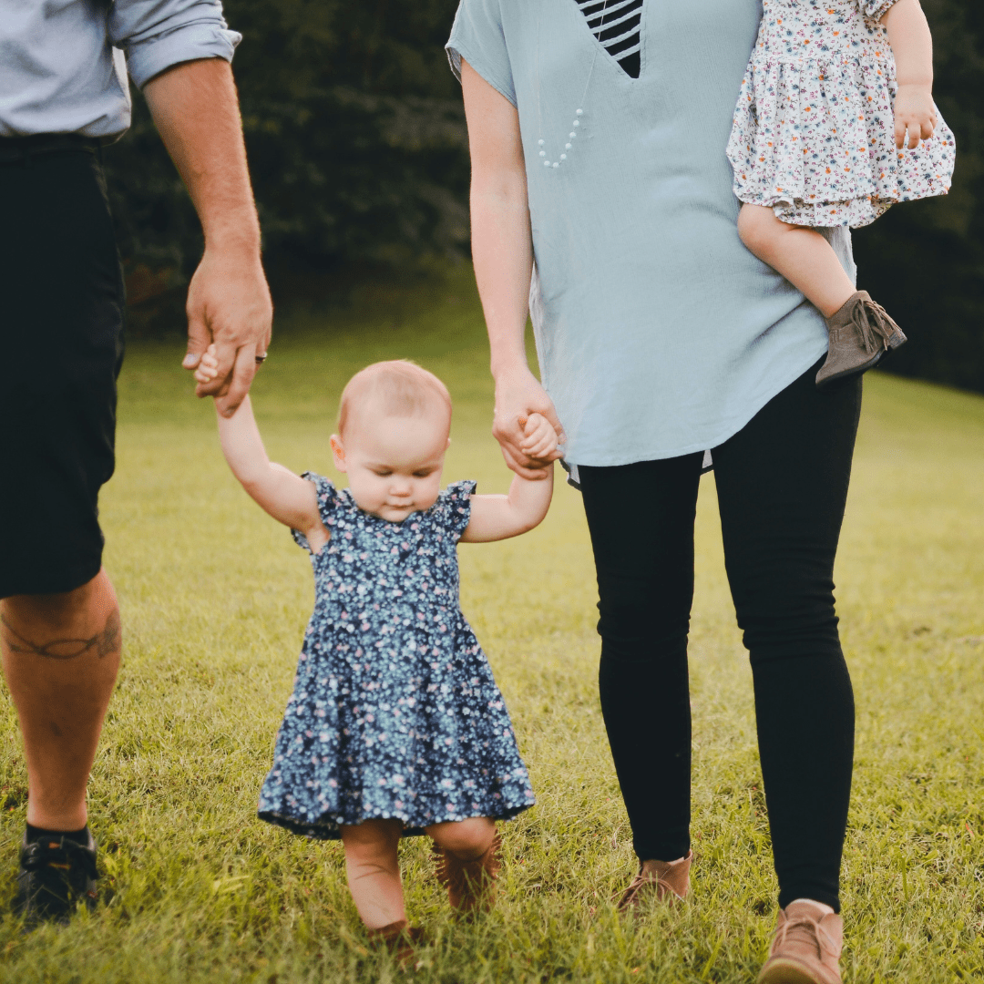 Parent holding baby's hand, mom one hand holds little baby