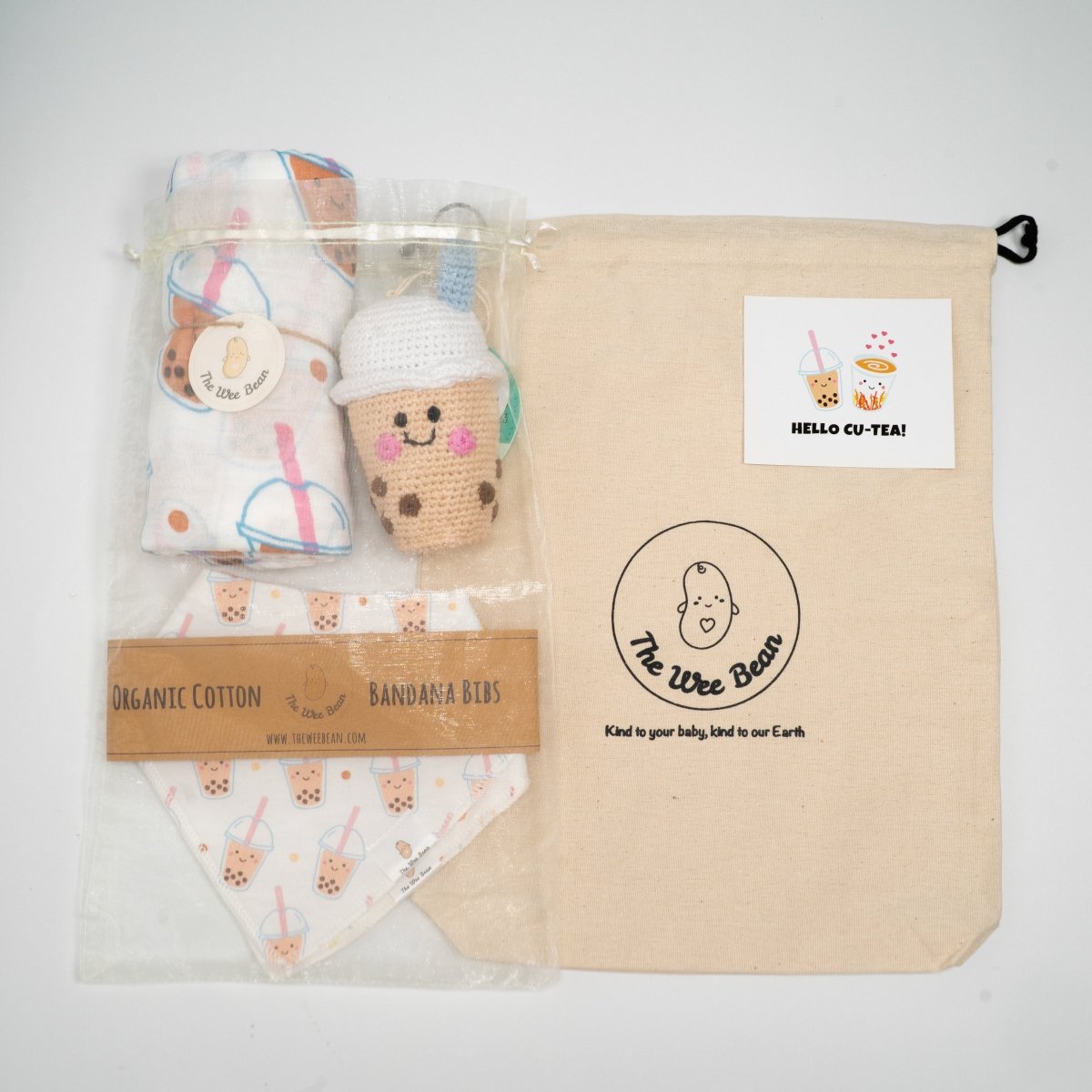 Baby product set with organic cotton bandana bibs, plush toy, and blanket in a branded bag.