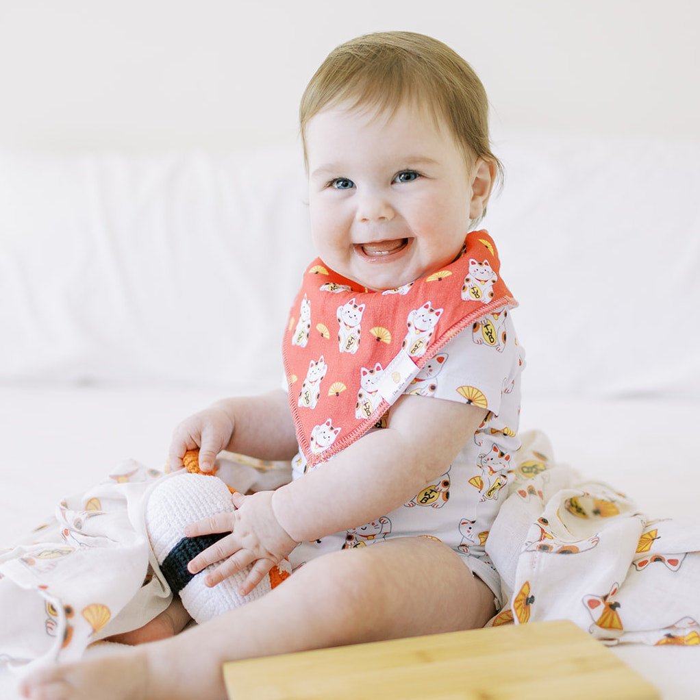 cute baby in lucky cat red bib sitting smiling