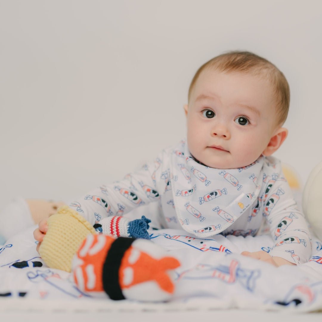 baby sitting on the wee bean minky blanket in white bunny candy while playing with toys