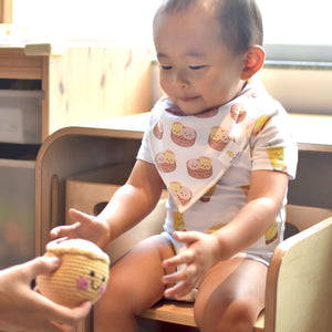 cute baby playing with fairtrade siu mai shumai doll in dim sum organic cotton bib