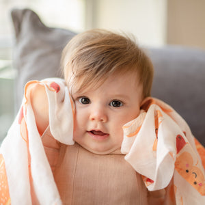 cute baby holding up organic cotton bamboo swaddle bakery buns
