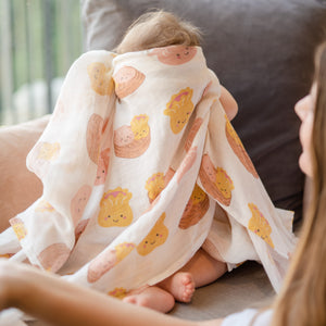 baby playing peekaboo in the wee bean organic cotton swaddle in dim sum