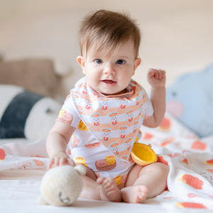 cute baby wearing the wee bean organic cotton bib in milk tea and onesie in dim sum