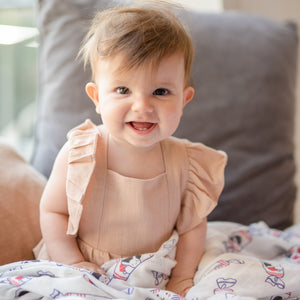 cute baby smiling while playing with organic cotton and bamboo swaddle in white rabbit candy
