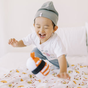 little boy playing with sushi doll on the organic cotton and bamboo lucky cat swaddle