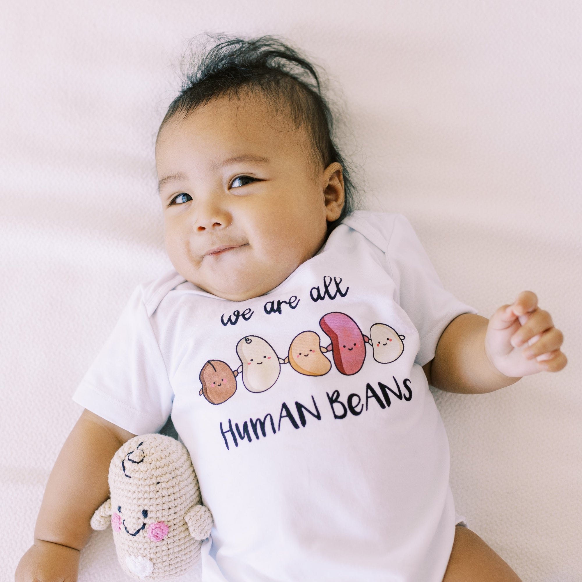 the wee bean organic cotton onesie in we are all human beans anti-hate anti-violence charity