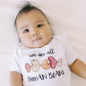 close up of the wee bean organic cotton baby onesie bodysuit in we are all human bean anti-hate anti asian hate