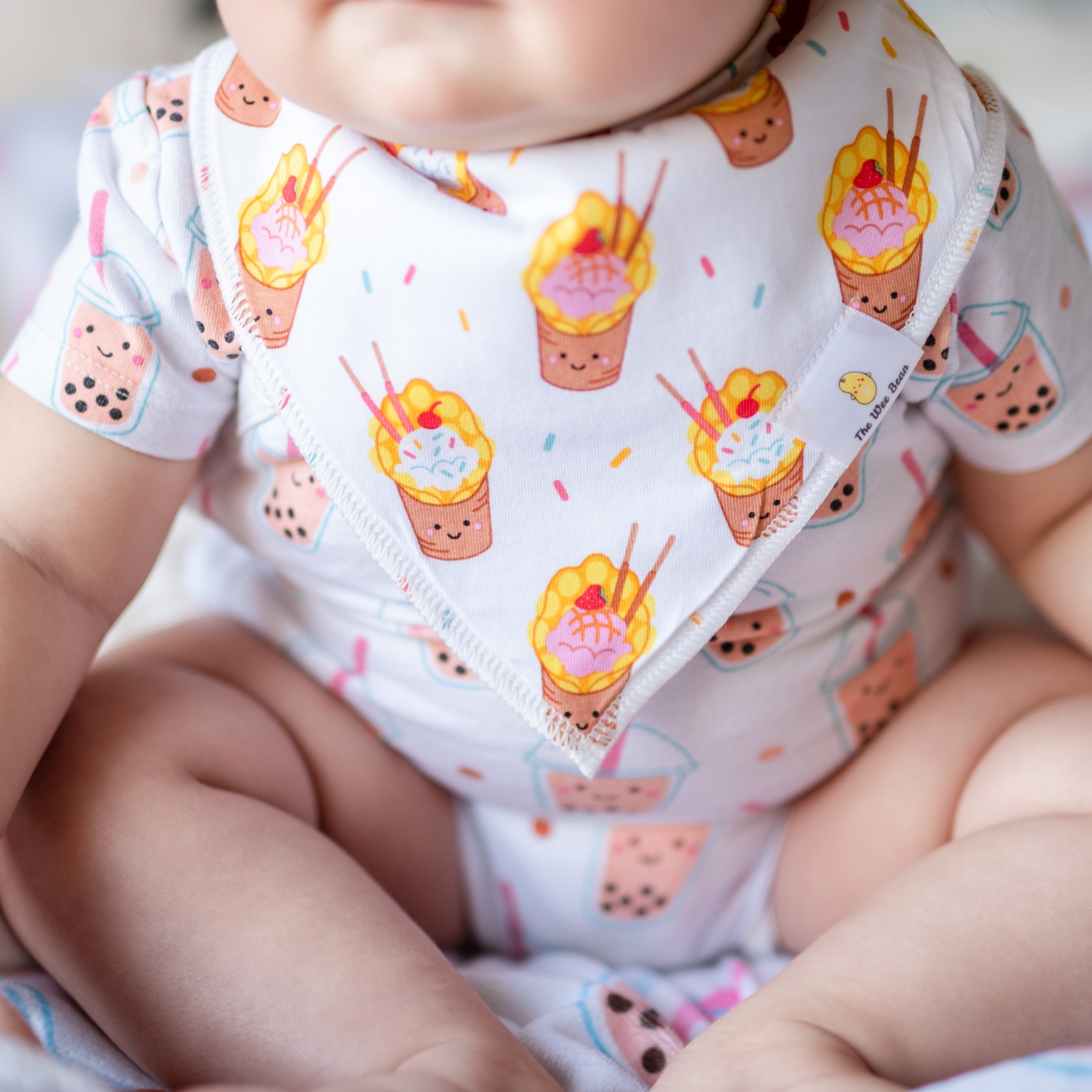 cute baby wearing the wee bean organic cotton bib in egg waffle sundae close up
